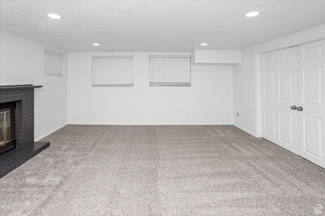 Finished basement featuring carpet floors, baseboards, a fireplace, and a textured ceiling | Image 28