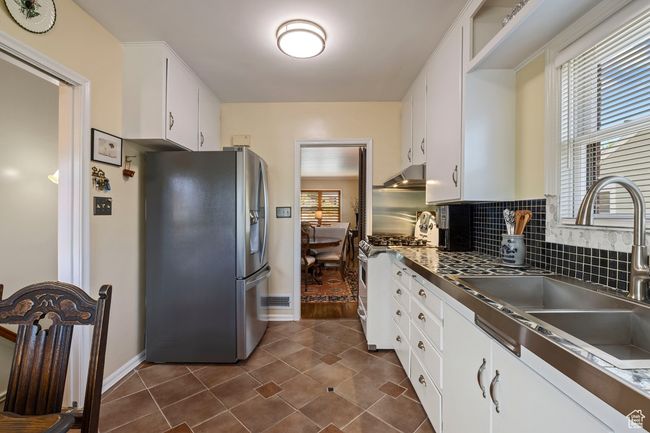 Kitchen featuring stainless steel appliances, plenty of natural light, white cabinets, and under cabinet range hood | Image 6