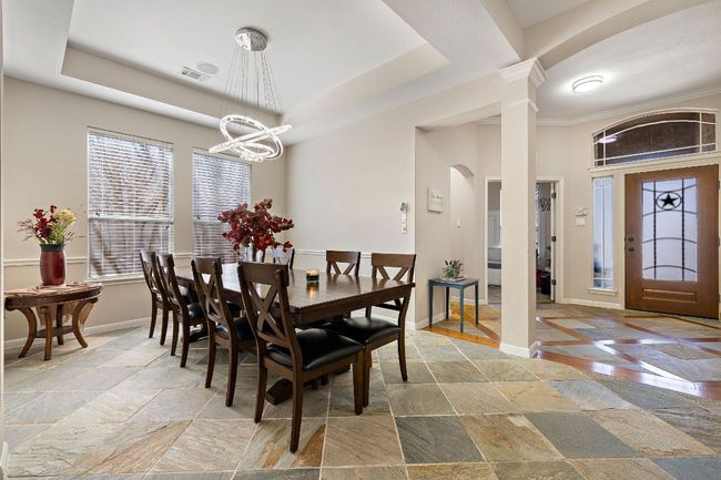 Dining room with arched walkways, a tray ceiling, baseboards, and stone tile floors | Image 4