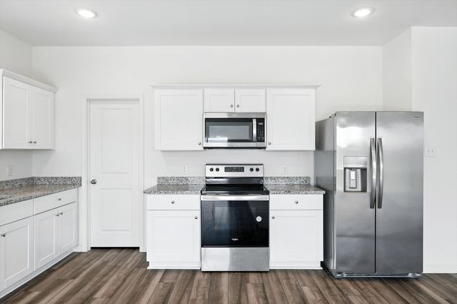 Kitchen with stainless steel appliances, dark wood-style floors, white cabinets, recessed lighting, and light stone counters | Image 8