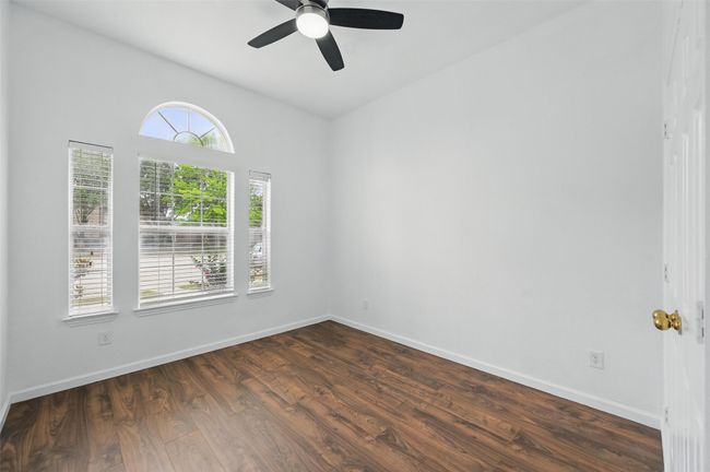 Unfurnished room with ceiling fan, dark wood finished floors, and baseboards | Image 8