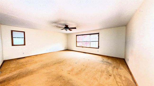Carpeted spare room featuring a textured ceiling, baseboards, and a ceiling fan | Image 18