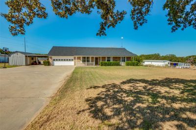 Single story home featuring covered porch, a garage, a front lawn, and a workshop | Image 1