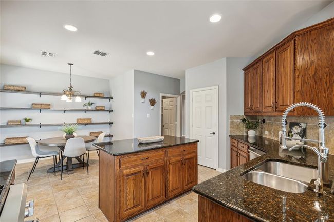 Kitchen featuring dark stone countertops, tasteful backsplash, sink, and light tile floors | Image 9