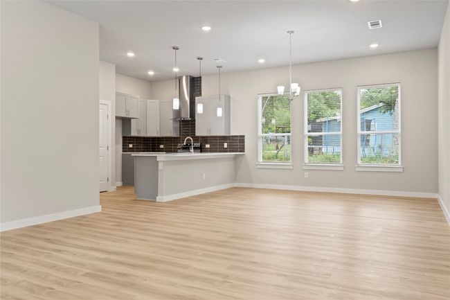 A stunning living space with an open floor plan, seamlessly blending the living, dining, and kitchen areas, bathed in natural light. | Image 5