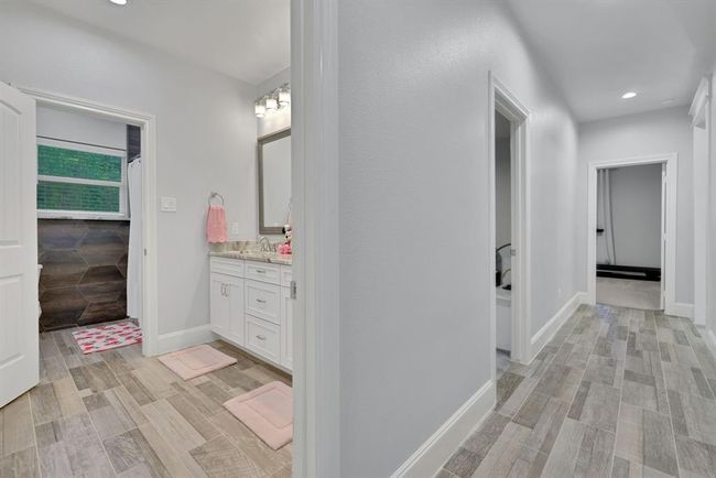 A thoughtfully designed hallway leads to three spacious secondary bedrooms and a luxurious dressing area, complete with a separate soaking tub and private water closet—offering comfort, privacy, and convenience for family or guests. | Image 30