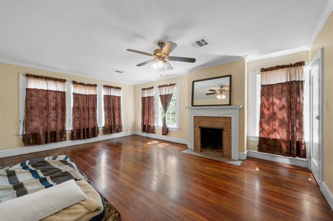 Unfurnished living room featuring ornamental molding, wood finished floors, a fireplace, and a ceiling fan | Image 21