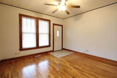 Empty room with wood-type flooring, ceiling fan, and crown molding | Image 2