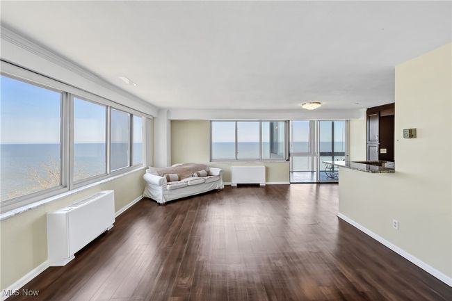 Unfurnished living room featuring dark wood-style floors, radiator, and baseboards | Image 4