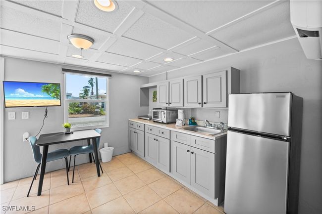 Kitchen featuring sink, stainless steel fridge, coffered ceiling, and gray cabinetry | Image 39