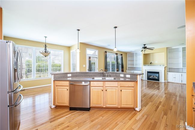 Kitchen with appliances with stainless steel finishes, light wood-type flooring, a glass covered fireplace, and a ceiling fan | Image 12