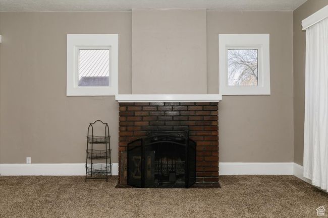 Empty room featuring a fireplace, visible vents, baseboards, a textured ceiling, and wood finished floors | Image 5