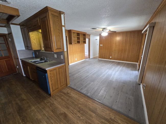 Kitchen featuring ceiling fan, dishwashing machine, dark wood finished floors, a textured ceiling, and wooden walls | Image 14