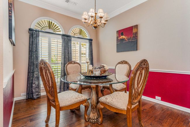 Dining area featuring crown molding, a chandelier, hardwood / wood-style floors, and baseboards | Image 8