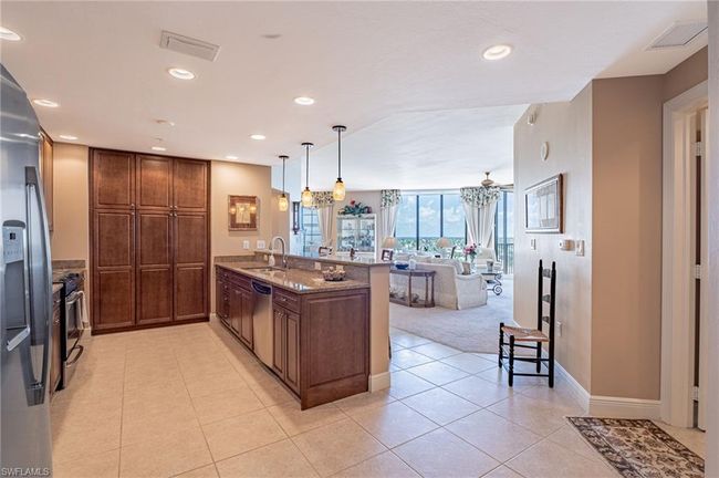 Kitchen with appliances with stainless steel finishes, sink, light stone counters, pendant lighting, and light tile patterned floors | Image 11