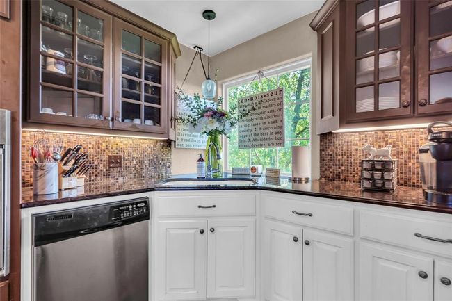 Kitchen with stainless steel dishwasher, a sink, dark stone counters, and tasteful backsplash | Image 14