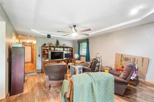 Living room featuring a ceiling fan, light wood finished floors, and a raised ceiling | Image 9