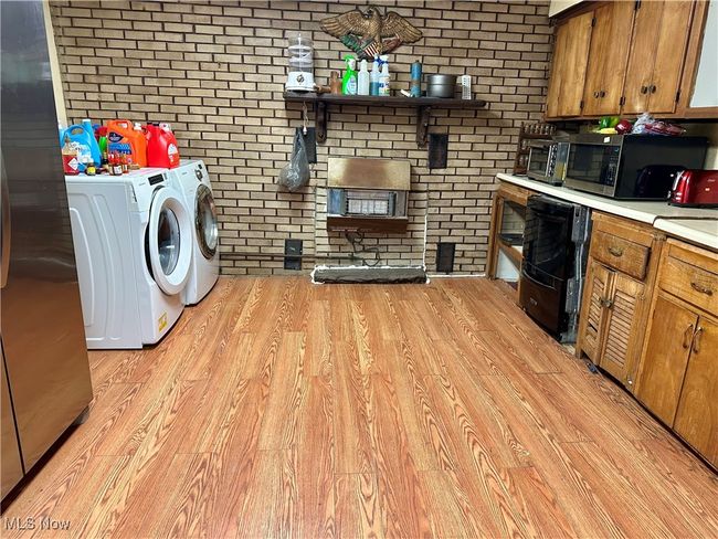 Washroom with washer and dryer, brick wall, laundry area, and light wood-style flooring | Image 10