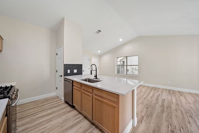Kitchen with stainless steel appliances, light wood-type flooring, a peninsula, vaulted ceiling, and light countertops | Image 15
