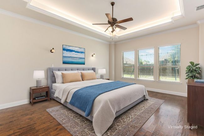 Bedroom with a raised ceiling, dark wood-type flooring, crown molding, baseboards, and ceiling fan | Image 7