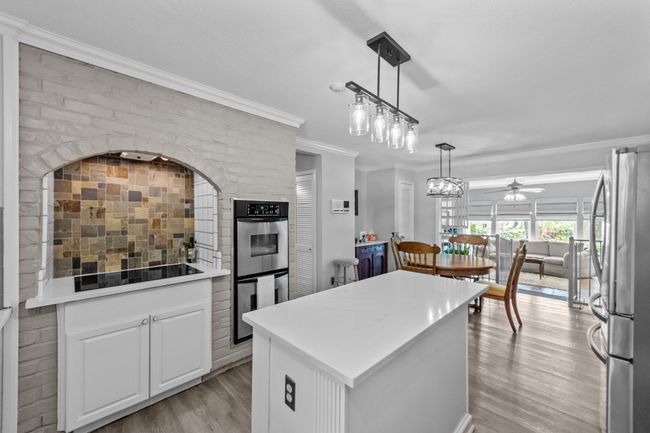 Kitchen with crown molding, light wood finished floors, a ceiling fan, appliances with stainless steel finishes, and a center island | Image 15