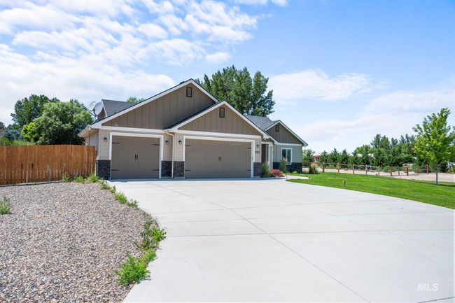 Craftsman house featuring board and batten siding, an attached garage, driveway, and stone siding | Image 43