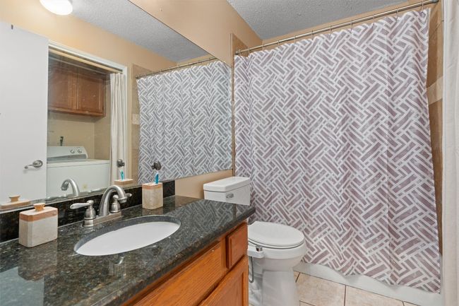 Bathroom featuring washer / clothes dryer, vanity, tile patterned floors, a textured ceiling, and curtained shower | Image 14