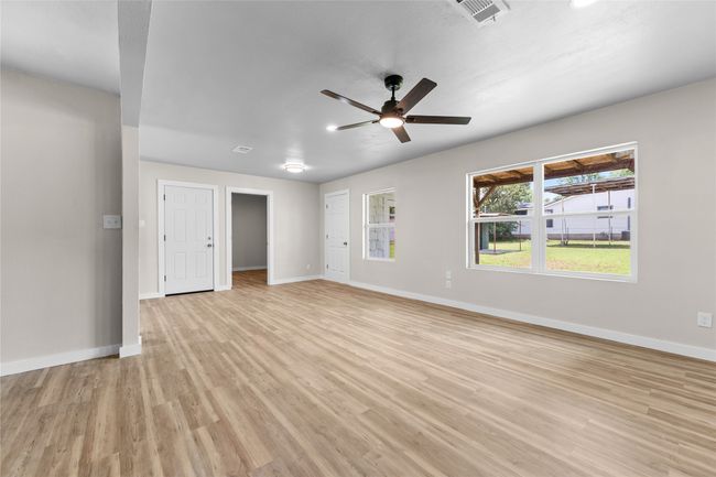 Unfurnished living room with light wood-style flooring, baseboards, and ceiling fan | Image 9