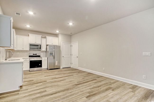 Kitchen featuring light wood-type flooring, white cabinetry, sink, and appliances with stainless steel finishes | Image 12