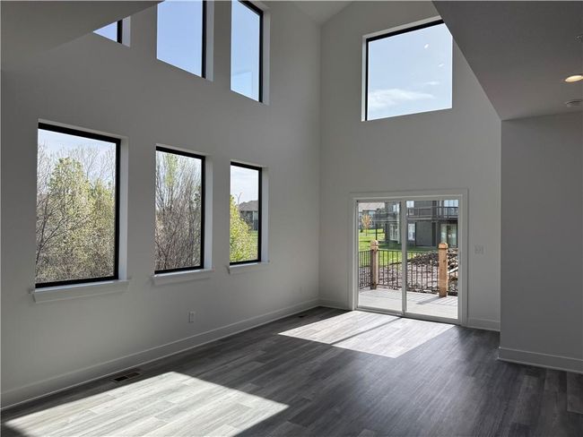 Unfurnished living room with baseboards, visible vents, a wealth of natural light, and wood finished floors | Image 10
