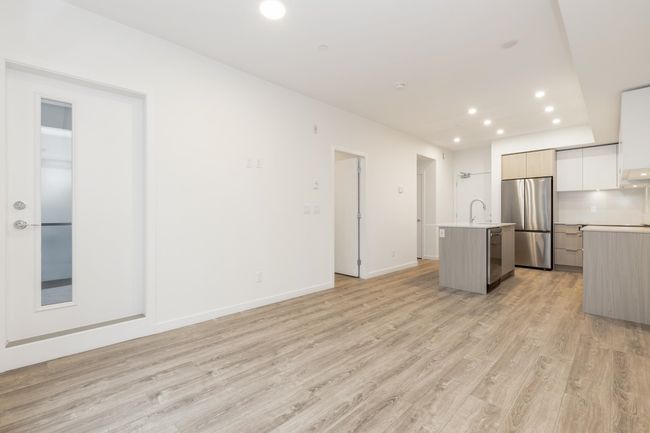 Kitchen with stainless steel appliances, modern cabinets, a center island with sink, light countertops, and light wood-style flooring | Image 5
