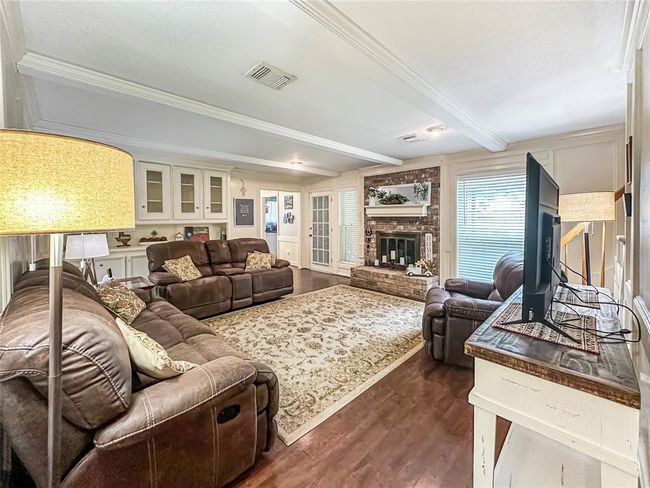 Brick fireplace offers extra seating, and the open ambiance is enhanced by large windows that bathe the space in sunlight, creating a bright and welcoming atmosphere. | Image 11