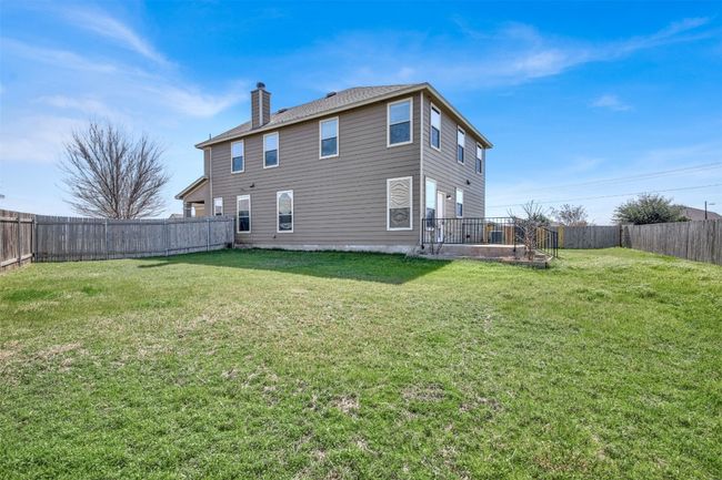Rear view of property featuring a fenced backyard, a chimney, and a yard | Image 35