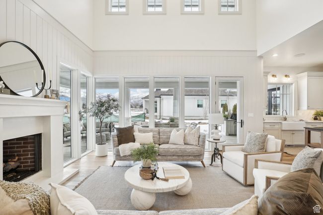 Living room featuring a fireplace with raised hearth, light wood-style flooring, and a high ceiling | Image 9