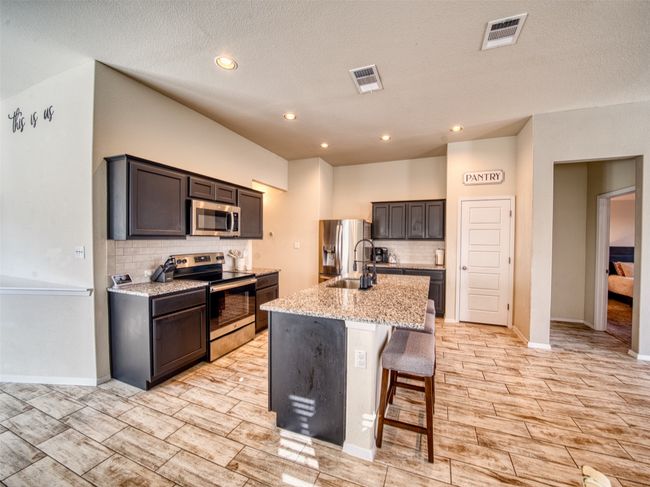 Kitchen featuring light stone countertops, sink, an island with sink, stainless steel appliances, and a breakfast bar​​‌​​​​‌​​‌‌​‌‌​​​‌‌​​‌‌​‌​​​​​‌ area | Image 7