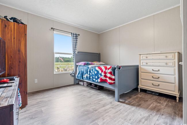 Bedroom featuring crown molding, a textured ceiling, wood finished floors, and a decorative wall | Image 25
