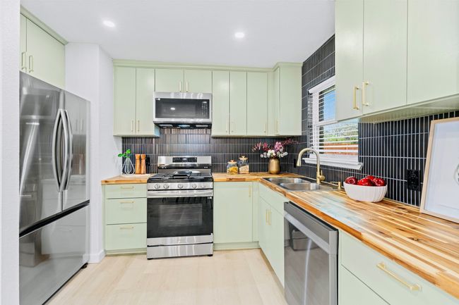 Kitchen featuring appliances with stainless steel finishes, wooden counters, tasteful backsplash, and recessed lighting | Image 13