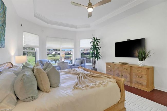 Bedroom featuring crown molding, multiple windows, a tray ceiling, and wood finished floors | Image 14