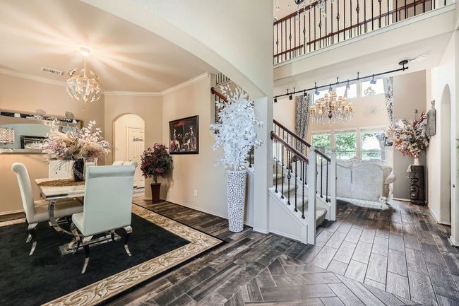 Dining area featuring a chandelier, arched walkways, a high ceiling, ornamental molding, and dark wood-type flooring | Image 12