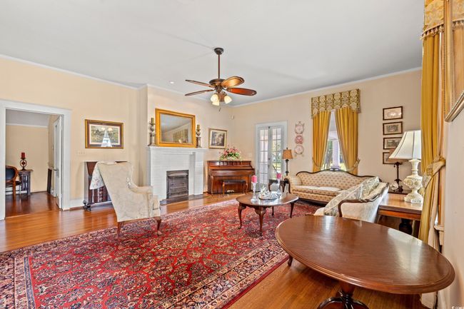 Living room featuring wood finished floors, ceiling fan, ornamental molding, and a fireplace | Image 5