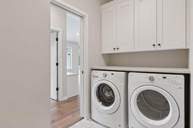 Such a smart design with laundry located off the primary bedroom closet featuring custom cabinets and folding counter | Image 30