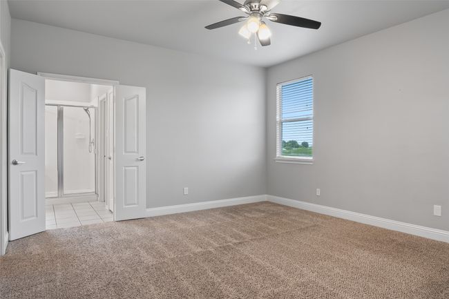Unfurnished bedroom with light colored carpet, baseboards, light tile patterned floors, and ceiling fan | Image 27