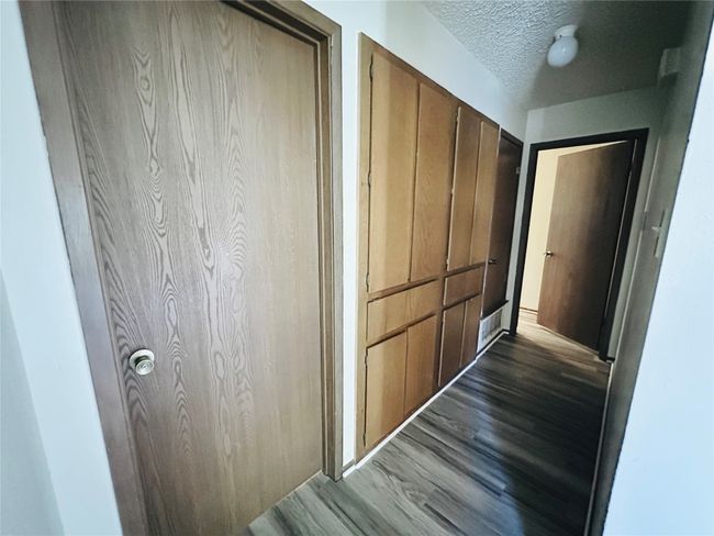 Corridor featuring a textured ceiling and dark wood-style flooring | Image 16