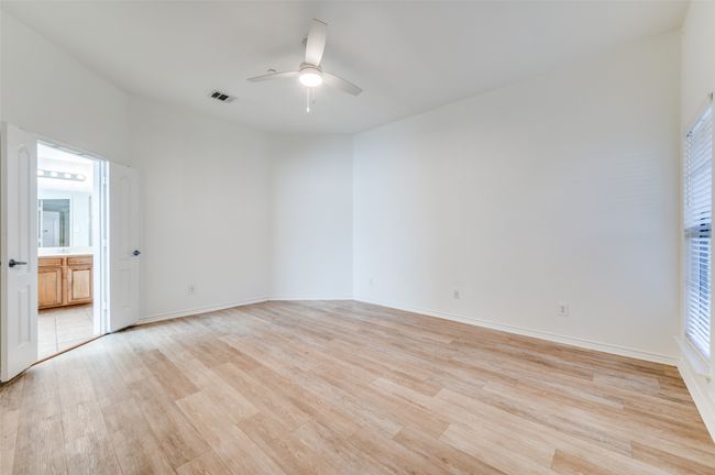 This expansive primary bathroom offers comfort and style with light laminate flooring that enhances its bright, open feel. The ensuite layout includes a large walk-in closet for convenient storage and organization. Designed for relaxation, this private retreat seamlessly combines function and elegance in a generous layout. | Image 16