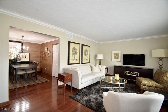 Living area featuring a chandelier, wood finished floors, ornamental molding, and baseboards | Image 5