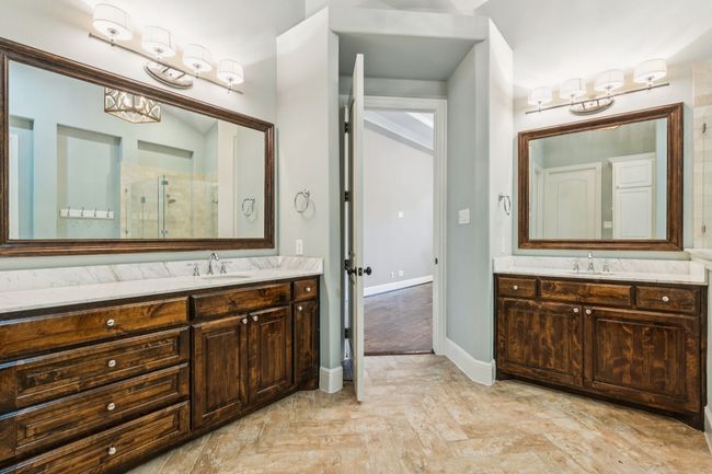 Primary bathroom featuring a glimpse of the shower, His and Her vanities | Image 17