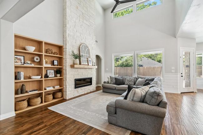 The expansive family room offers a focal point in its stone fireplace, complemented by practical built-in shelving. | Image 11