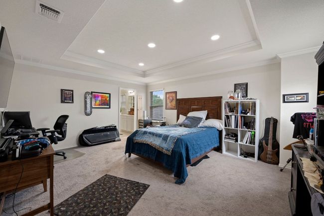 Carpeted bedroom with a raised ceiling, ornamental molding, and visible vents | Image 13