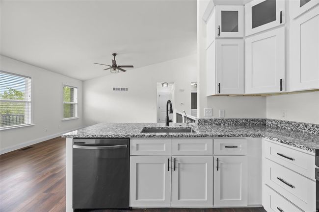 Kitchen with stainless steel dishwasher, a ceiling fan, a peninsula, white cabinetry, and a sink | Image 30