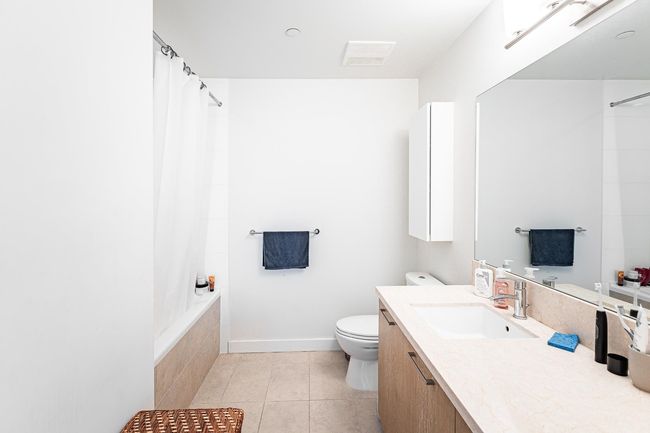 Bathroom with toilet, vanity, tile patterned flooring, tiled shower / bath combo, and baseboards | Image 11